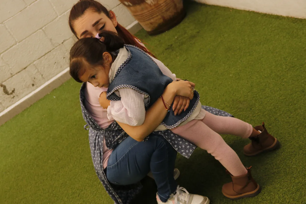 Guía Montessori abrazando una niña en el patio de la escuela.